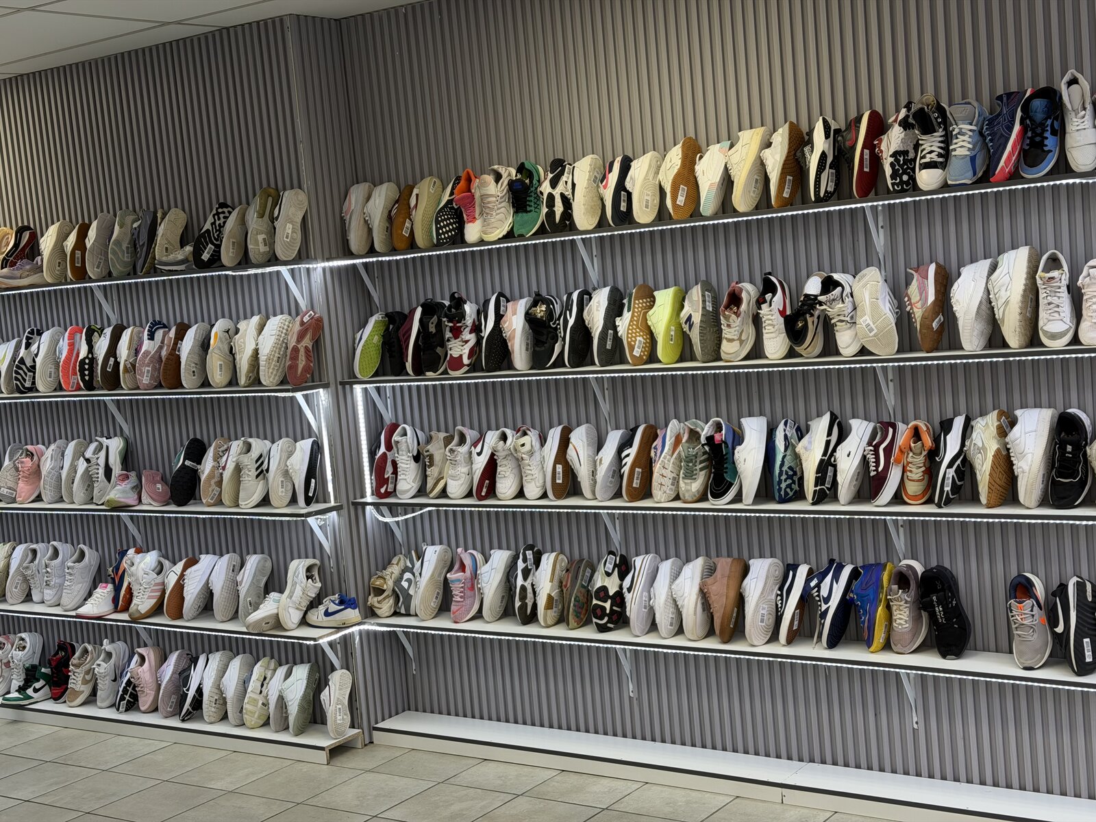 Wall of second-hand sneakers on shelves at Second Step Couture